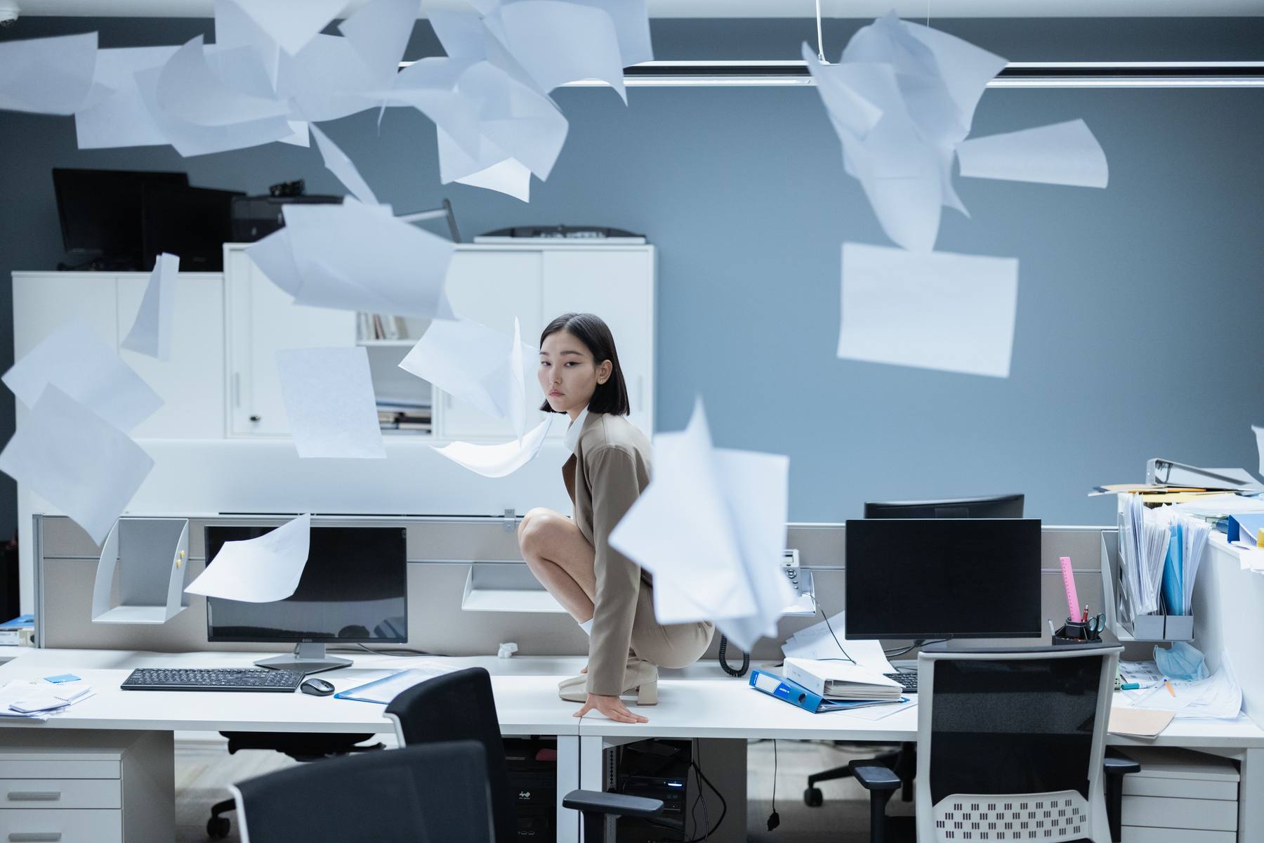Une juriste sereine au milieu de feuilles qui volent dans un bureau