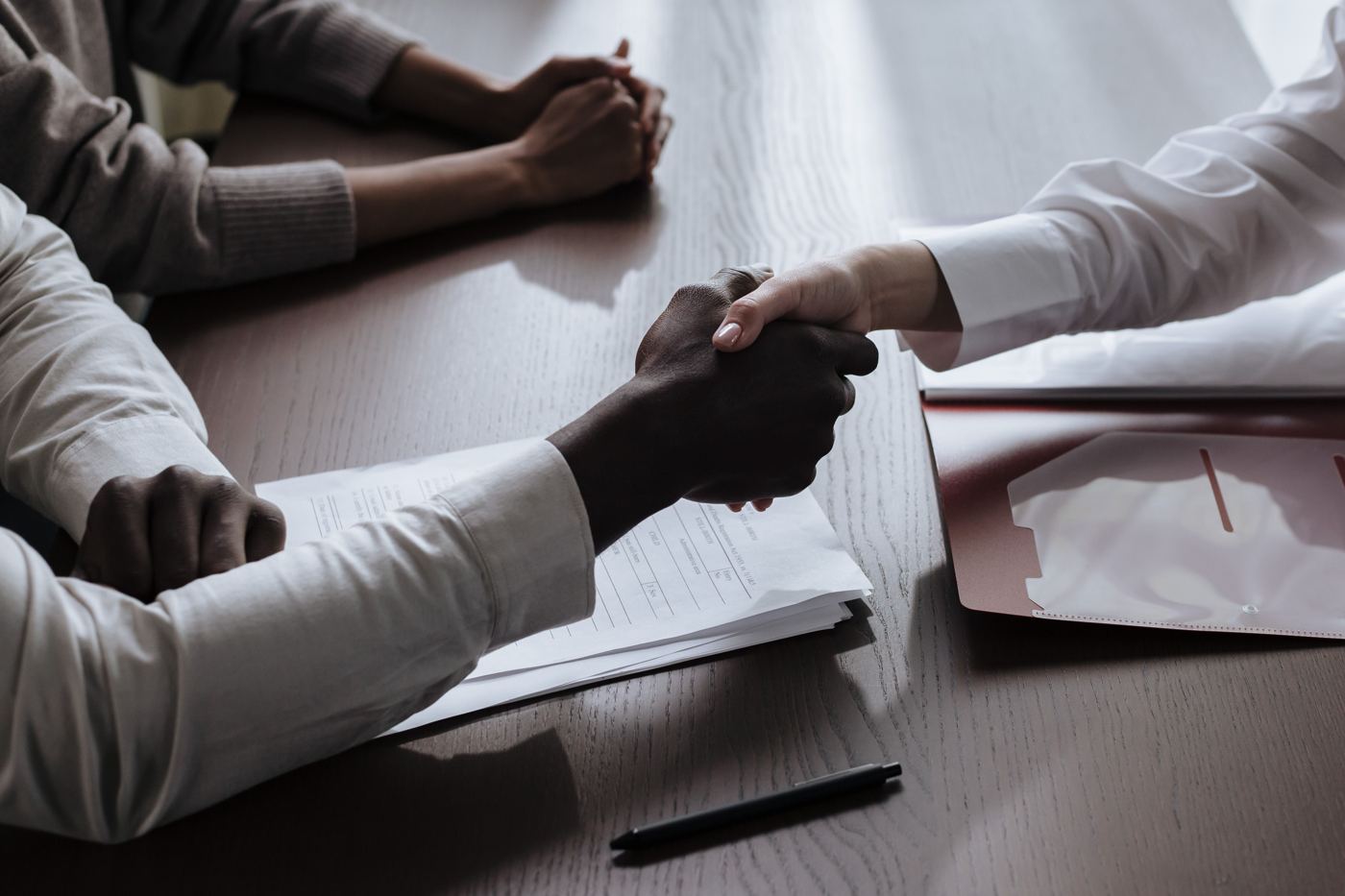 Deux personnes échangeant des documents sur une table de réunion